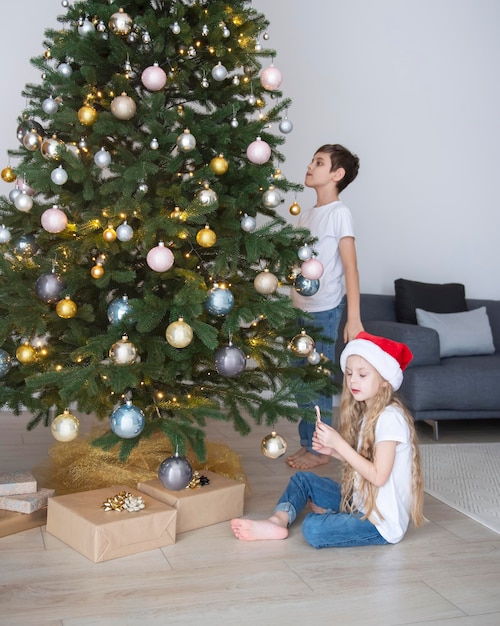 Kinderen een jongen en een meisje spelen bij de kerstboom