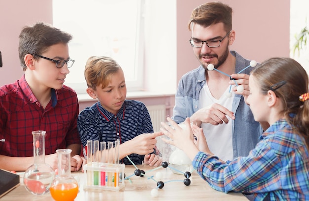 Kinderen en wetenschap. Pre-tienerstudenten onderzoeken moleculaire structuur met leraar in laboratorium met vloeistoffen, reageerbuizen en kolven. Stemonderwijs, E-learning