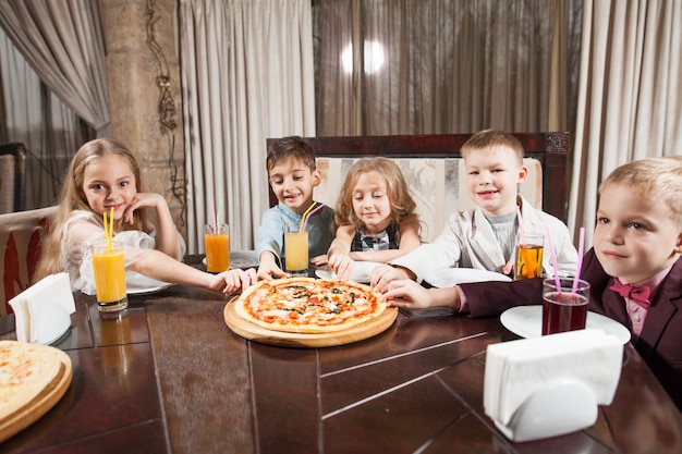 Kinderen eten pizza in een restaurant.