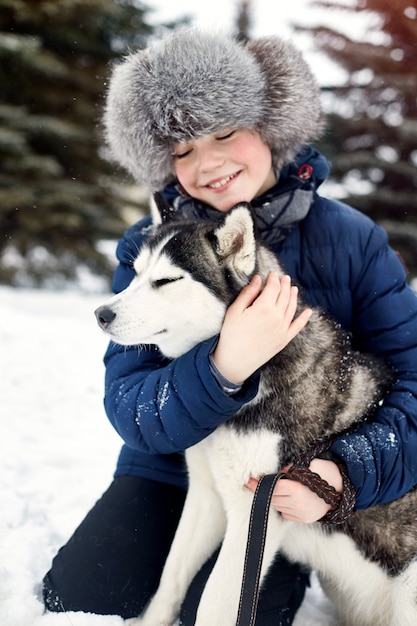 Kinderen gaan in de winter uit met husky's. Kinderen zitten in de sneeuw en streelden hond husky