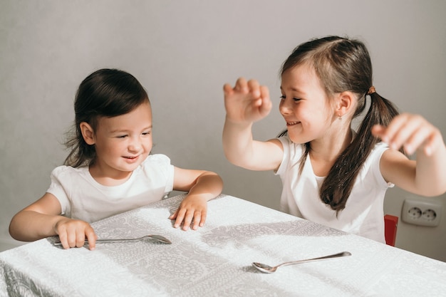 Kinderen genieten aan tafel. Twee zussen wachten op eten