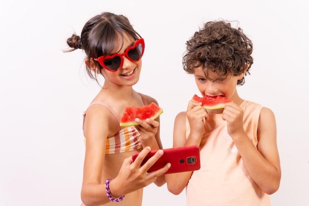 Kinderen genieten van de zomer die een watermeloen eten en een selfie maken met de telefoon witte achtergrond