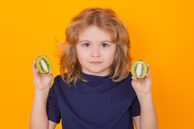 Kinderen gezicht met fruit Kinderen houden kiwi in studio Kiwi's Studio portret van schattige jongen jongen met kiwi geïsoleerd op geel