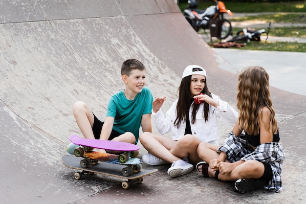 Kinderen glimlachen en lachen en hebben samen plezier Kinderen met skateboard en pennyboards communiceren en discussiëren op de sportspeeltuin Jongen en meisjes vriendschapsconcept