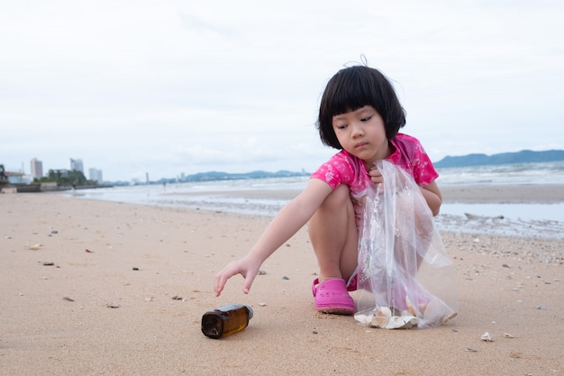 Kinderen halen afval op het strand, vuile zee