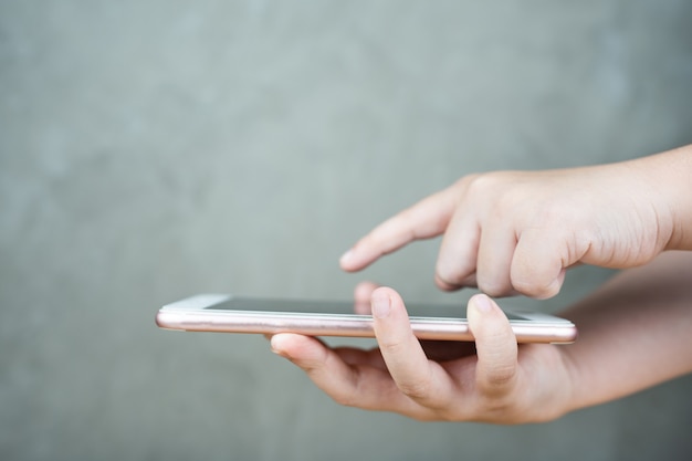 Foto kinderen hand met mobiele smartphone met touchscreen op grijs beton