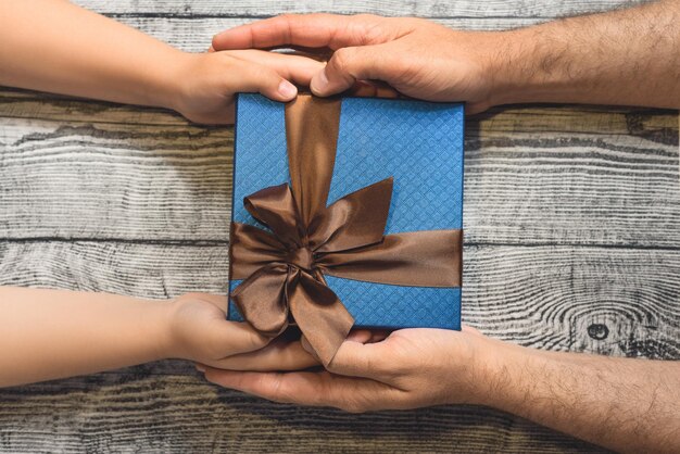 Kinderen handen met een geschenk op de houten achtergrond