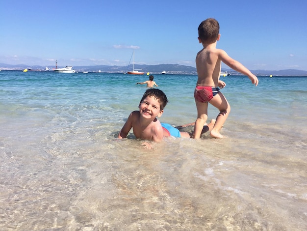 Kinderen hebben plezier in het strandwater. Kinderen lachen tijdens het spelen in de zee.