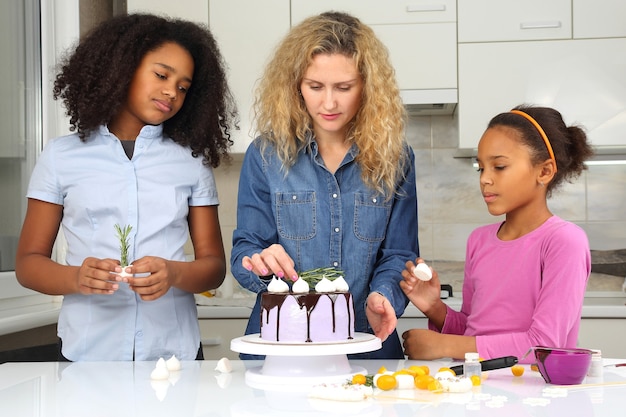 Kinderen helpen mama met het versieren van de taart