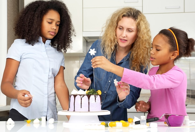 Kinderen helpen mama met het versieren van de taart