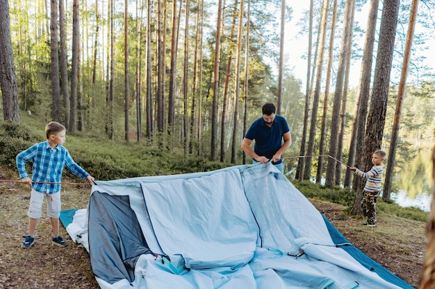 kinderen helpen vader om een tent op te zetten gezinscamping concept