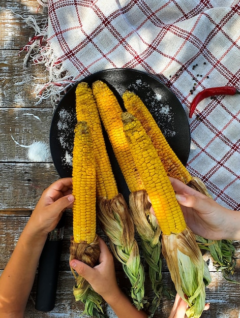 Kinderen houden hete kolven vers gegrilde mais in hun handen