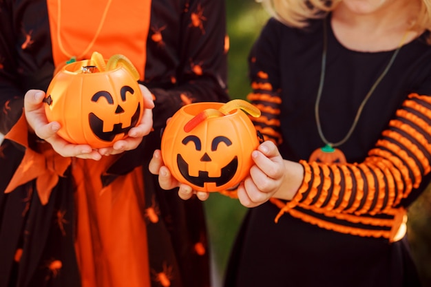 Kinderen houden twee pompoenen jackolanterns met snoepjes kinderen dragen halloweenkostuums