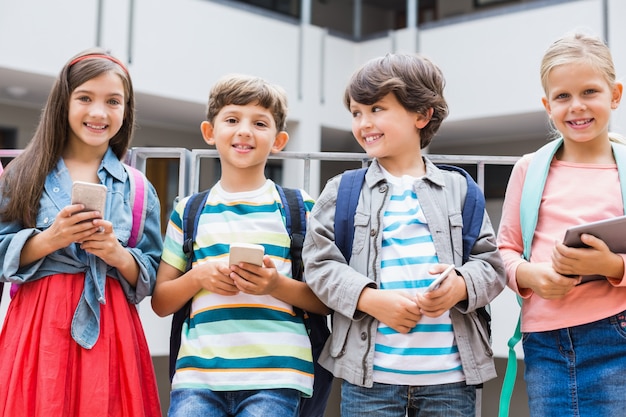 Kinderen houden van mobiele telefoon en digitale tablet staande op schoolterras