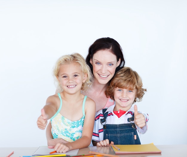 Kinderen huiswerk met hun moeder met duimen omhoog