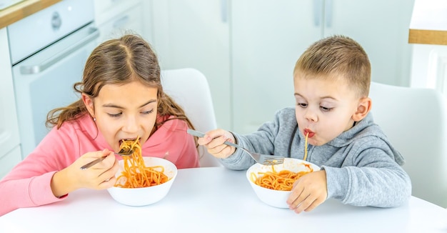 Kinderen in de keuken aan tafel draaien pasta selectieve focus