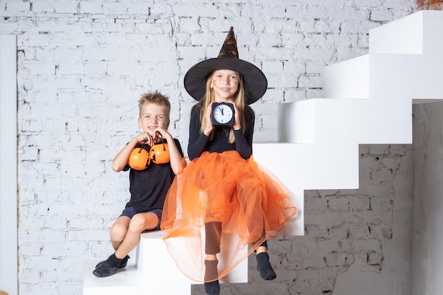 Kinderen in griezelige heksenkostuums en hoeden houden een zwarte wekker en een pompoenvormige mand vast