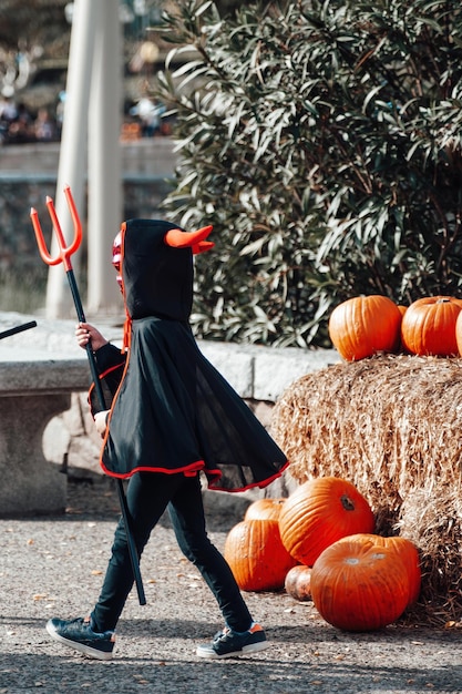 Foto kinderen in halloween-kostuums op vakantie meisje in heksenpak, zwarte hoed en jongen in duivelskostuum met eng masker en drietand kinderen spelen op allerheiligenavond in feestkleding in openluchtpark