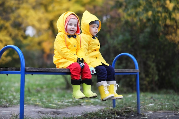 Kinderen in het herfstpark lopen overdag in regenjassen