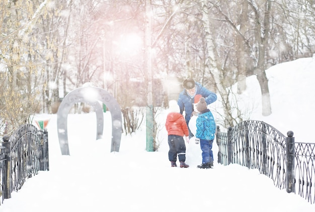 Kinderen in het park in de winter. Kinderen spelen met sneeuw op de speelplaats. Ze boetseren sneeuwmannen en glijden van de heuvels.