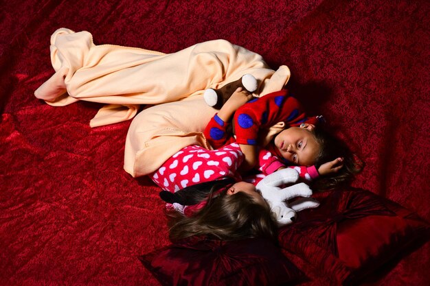 Kinderen in pyjama knuffelen samen met teddyberen op rood