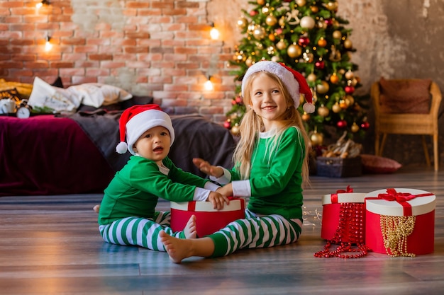 Kinderen in pyjama's en kerstmutsen pakken kerstcadeautjes uit