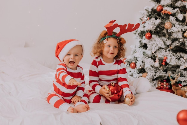 Kinderen in rood-witte pyjama's spelen, hebben plezier, trekken gezichten in bed. broer en zus, jongen en meisje die Kerstmis vieren. levensstijl. ruimte voor tekst. Hoge kwaliteit foto