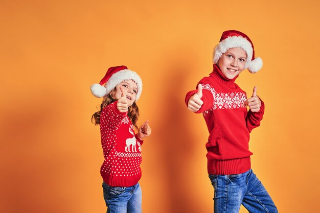 Kinderen in Santa hoeden met duimen omhoog