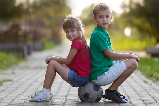 Foto kinderen jongen en meisje zittend op voetbal