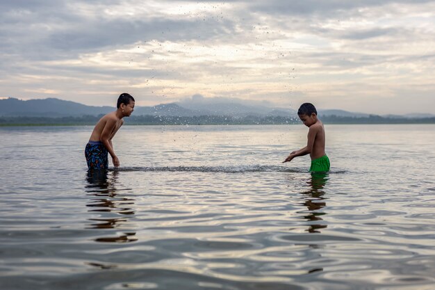 Kinderen jongen spelen in het water is gelukkig en leuk.