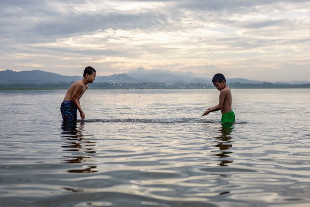 Kinderen jongen spelen in het water is gelukkig en leuk.