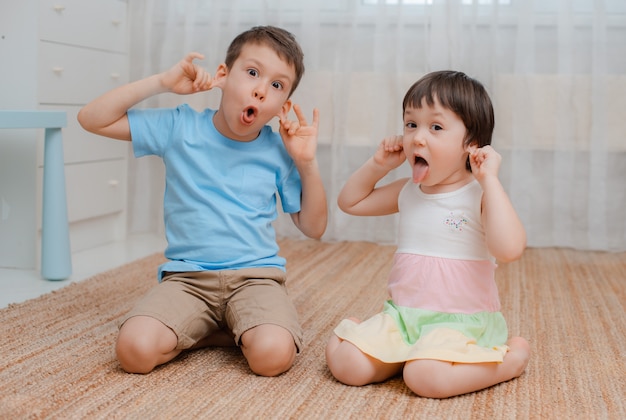 Kinderen, jongensmeisje, stoute vloerruimte ze lachen grimas.