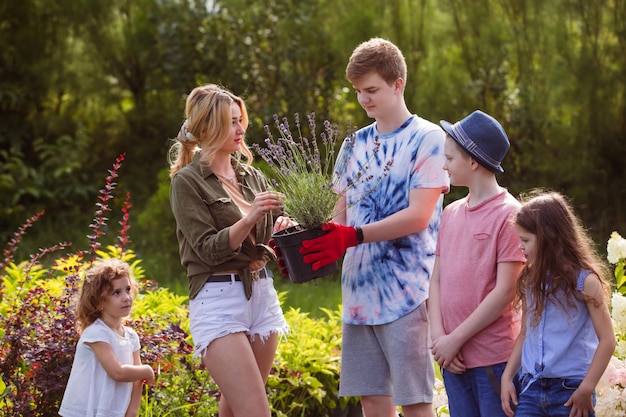 Kinderen kiezen planten voor hun tuin op de buitenbloemenmarkt Verkoopster biedt bloemen aan de klant Kinderen kiezen cadeau voor moederdag