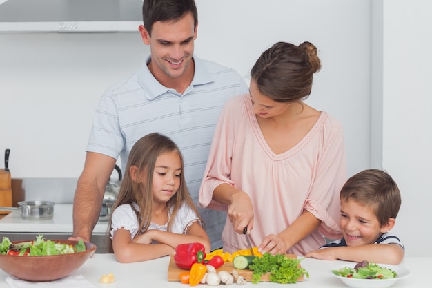 Kinderen kijken naar hun moeder die groenten aan het klaarmaken is