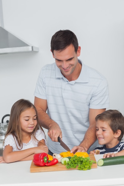 Kinderen kijken naar hun vader die groenten snijdt