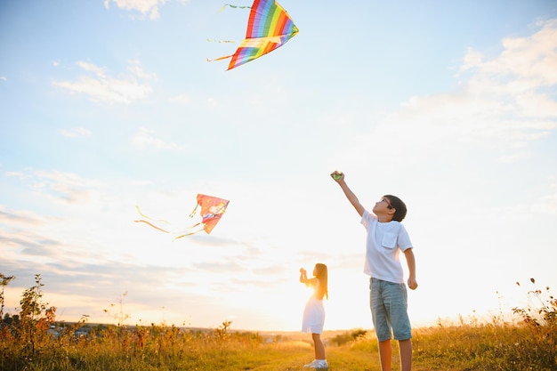 Kinderen lanceren een vlieger in het veld bij zonsondergang