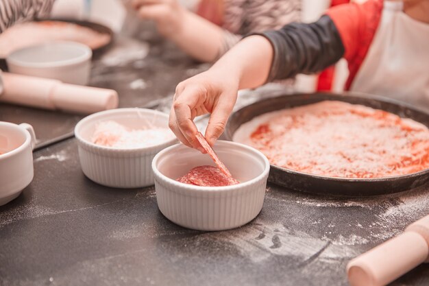 kinderen leggen de ingrediënten neer op basis van pizza