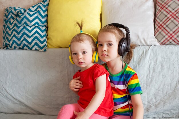 Kinderen leren engels met een koptelefoon. twee meisjes luisteren naar muziek op een koptelefoon