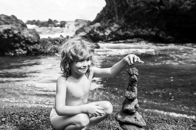 Kinderen leren kiezelstenen toren of piramide op water sorteren of stapelen voor evenwichtstraining en meditatie met natuurkinderen ontspannen op zomervakantie