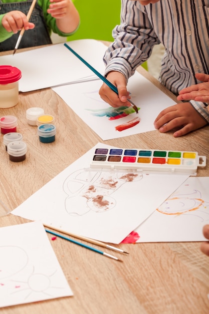 Kinderen leren schilderen met een penseel en aquarellen op papier in de kleuterschool