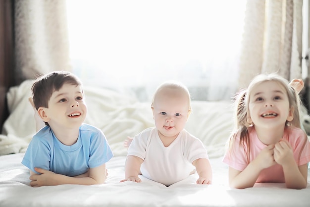 Kinderen liggen op het bed naast de pasgeboren baby, zusje. De emoties van kinderen.