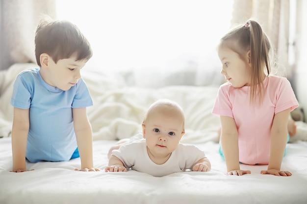 Kinderen liggen op het bed naast de pasgeboren baby, zusje. Emoties van kinderen.