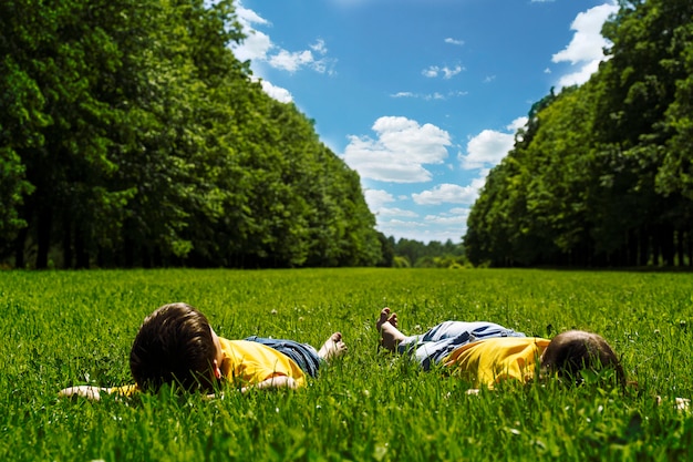 Kinderen liggen op het felgroene gras en glimlachen. kinderdag.