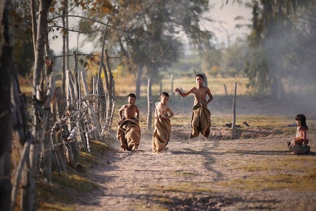 Kinderen lopen in de zak, kinderen spelen traditionele sporten in het oude Thailand, landelijke land