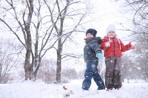 Kinderen lopen in het park met eerste sneeuw
