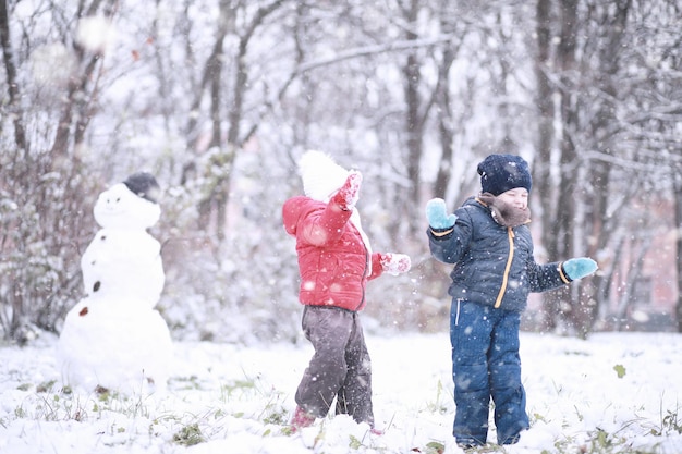 Kinderen lopen in het park met eerste sneeuw