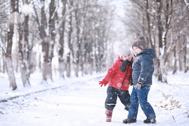 Kinderen lopen in het park met eerste sneeuw