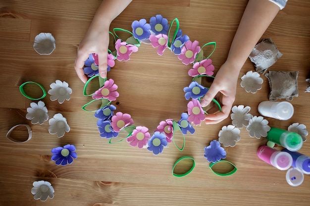 Kinderen maken een paasbloemenkrans in pastelkleuren met behulp van een upcycled eierspoor zonder afvallevensstijl