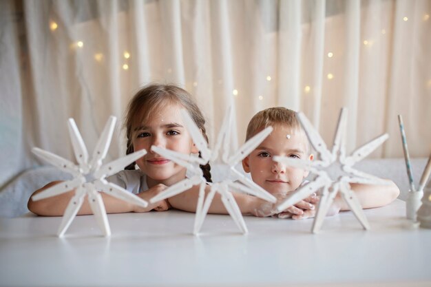 Kinderen maken kerstsneeuwvlokken van wasknijper herbruikbare originele ornament diy nieuwjaarsdecoratie