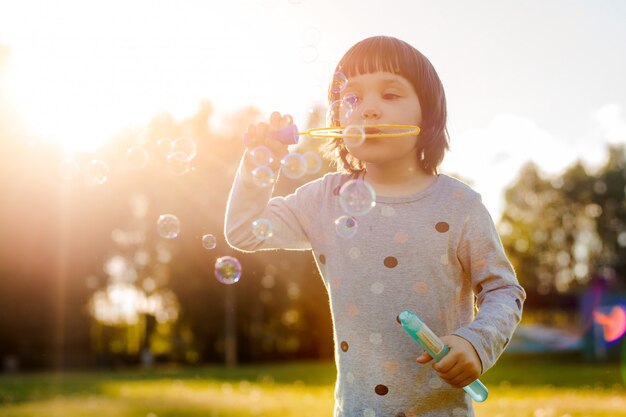 Kinderen meisje bellen blazen op de speelplaats met zonsondergang